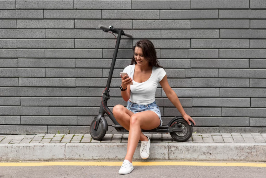 a girl in white shirt and blue shorts is sitting on a black electric scooter