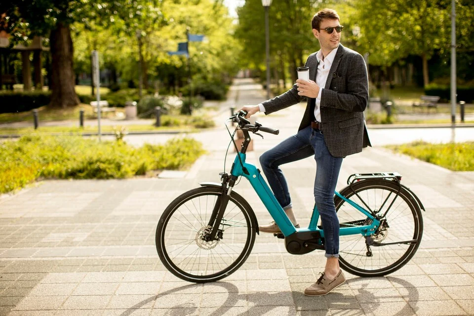 A man is riding a bike with a cup of coffee.