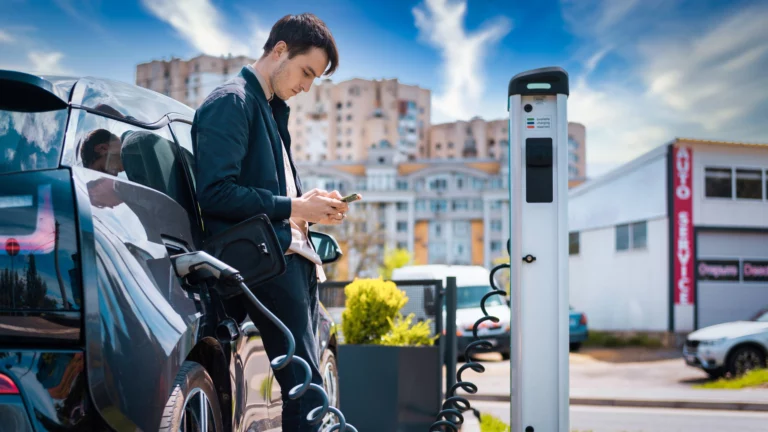 Man charging his electric car charge station using smartphone.