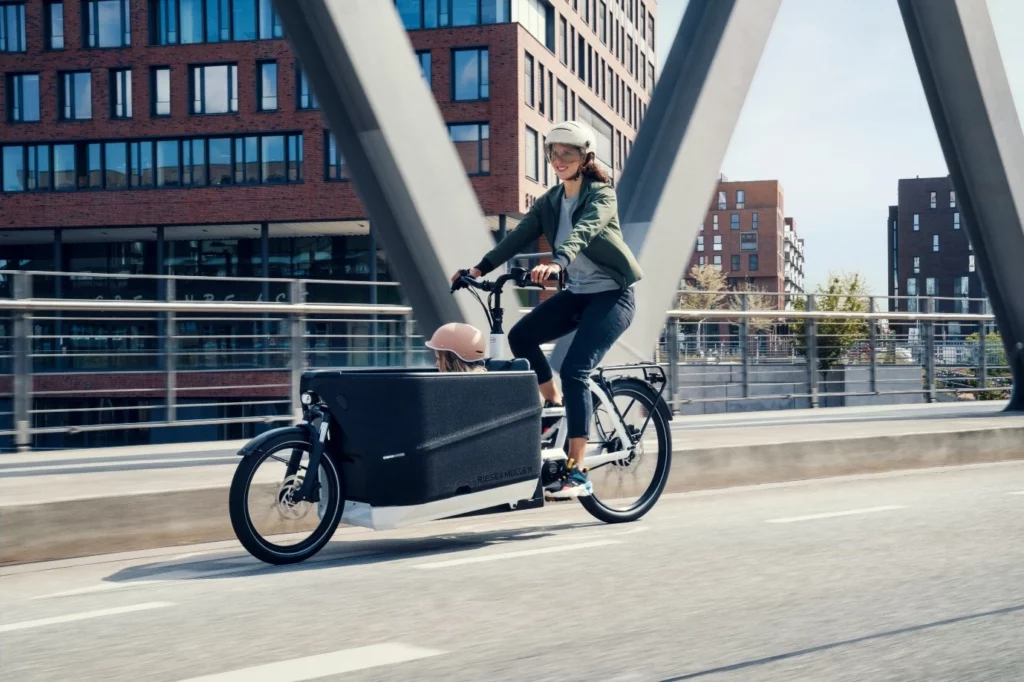 A woman ride a Electric cargo bike on the road.