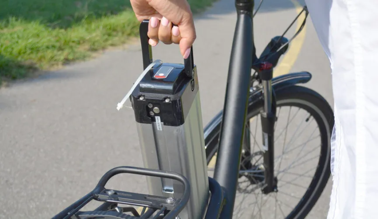 removing the ebike battery from a standing black colored electric bike